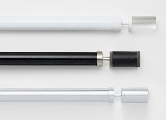 Three drapery hardware options in various Acero finishes laid out on a white table top