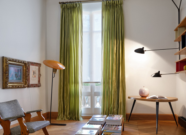 A window featuring goblet drapery in silk dupioni leaf in a lounge room with grey seating, a coffee table and wall art
