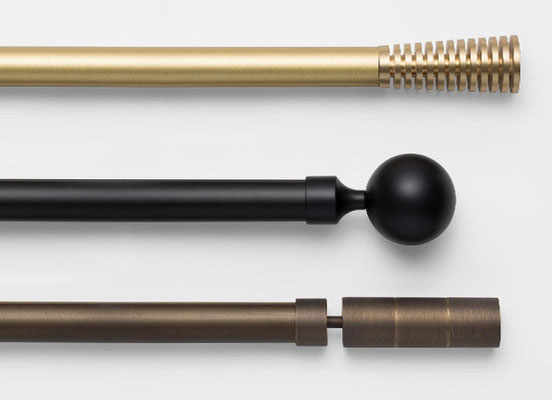 Three drapery hardware options in various Madison finishes laid out on a white table top
