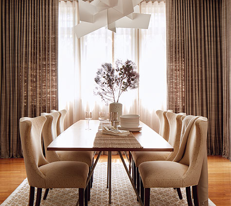 Layering curtain styles, one of the most popular window treatment designs, is seen in this dining room's two layers of Ripple Fold Drapery