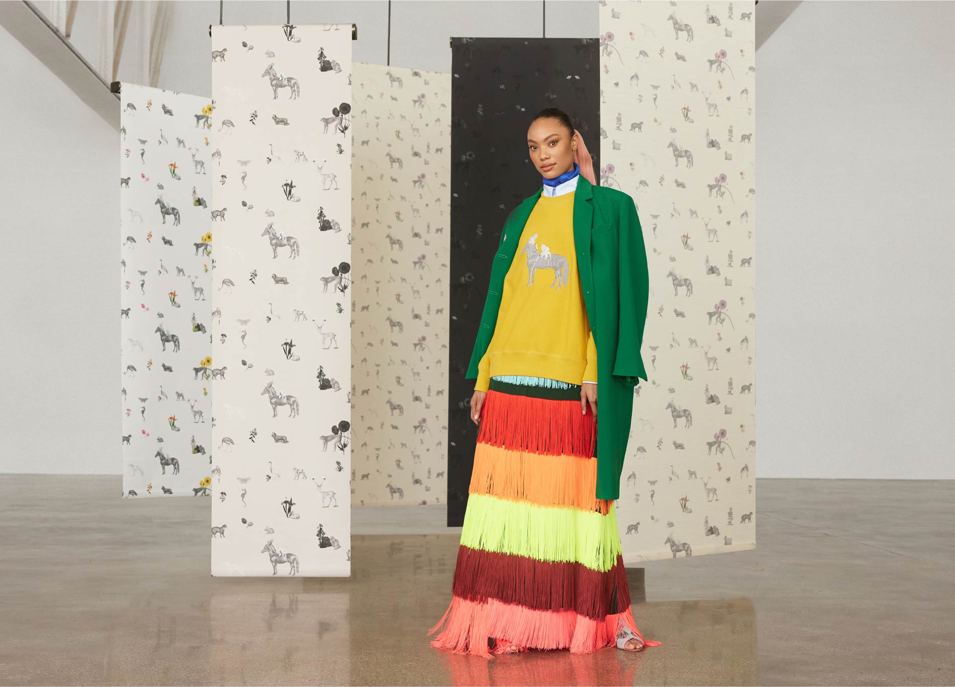 A model in a colorful Mimi Plange outfit standing in front of the Mimi Plange collection materials