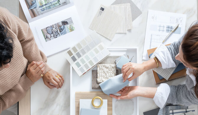 Two women sit at a table comparing swatches and colors during a design consultation with The Shade Store Design Consultant
