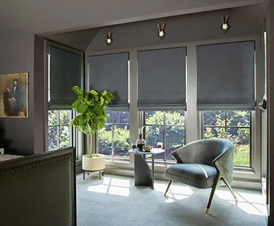 A dark modern bedroom features modern window shades using flat roman shades made from wool sateen in a dark grey