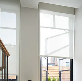 A bright foyer has privacy shades in the Solar Shade style made of 10% White material that softens light without dimming it as solar window coverings for glare reduction and daytime privacy